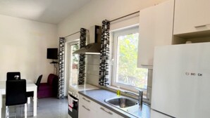 A compact kitchen with a Bosch refrigerator, a window with a view, and a dining area with a table and chairs. - Paradise Apartments-Studio apartman with sea view and terrace 2 (Gdinj)