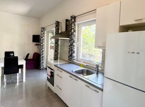 A compact kitchen with a Bosch refrigerator, a window with a view, and a dining area with a table and chairs. - Paradise Apartments-Studio apartman with sea view and terrace 2 (Gdinj)