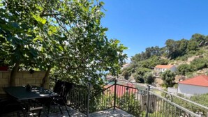 A balcony with a table and chairs, a tree, and a view of a hillside with houses. - Paradise Apartments-Studio apartman with sea view and terrace 2 (Gdinj)