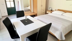 A hotel room with a bed, a desk, a chair, a wardrobe, and a mirror. - Paradise Apartments-Studio apartman with sea view and terrace 2 (Gdinj)