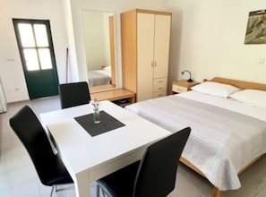 A hotel room with a bed, a desk, a chair, a wardrobe, and a mirror. - Paradise Apartments-Studio apartman with sea view and terrace 2 (Gdinj)