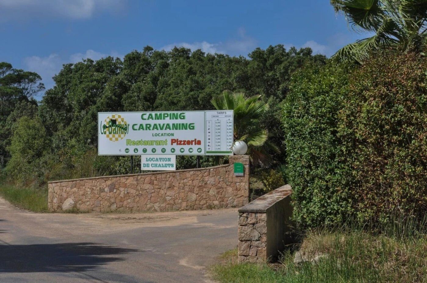 A sign for a camping and caravanning location with a restaurant and pizzeria.