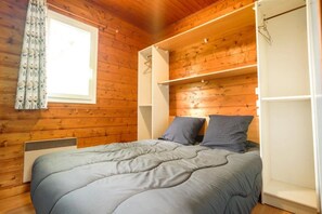 Une chambre à coucher avec un lit, une fenêtre avec des rideaux et des murs en bois.