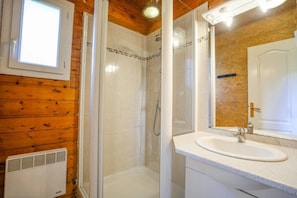 Une salle de bain avec une douche, un lavabo et une fenêtre.