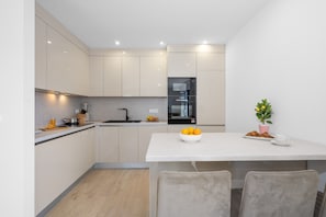 A modern kitchen with a white countertop, a sink, and a dining area with two chairs. - Three Bedroom Villa with Outdoor Swimming Pool (Vodice)