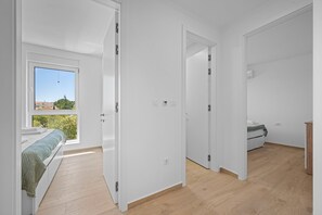 Ein Schlafzimmer mit Bett, Fenster und Blick ins Grüne.