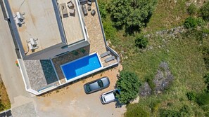 Luftaufnahme eines Wohnhauses mit Swimmingpool, zwei Autos und einer Terrassenanlage.