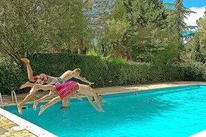 A swimming pool with clear blue water, surrounded by lush greenery and trees.