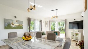 A modern dining area with a marble table, grey upholstered chairs, and a fruit bowl. - Villa with mountain view (Lovreć)