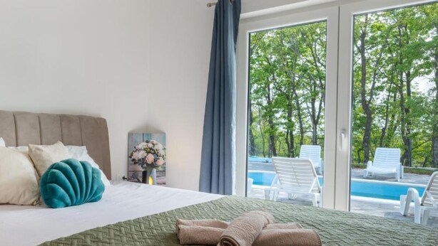 A hotel room with a bed, a view of a swimming pool, and a balcony. - Villa with mountain view (Lovreć)