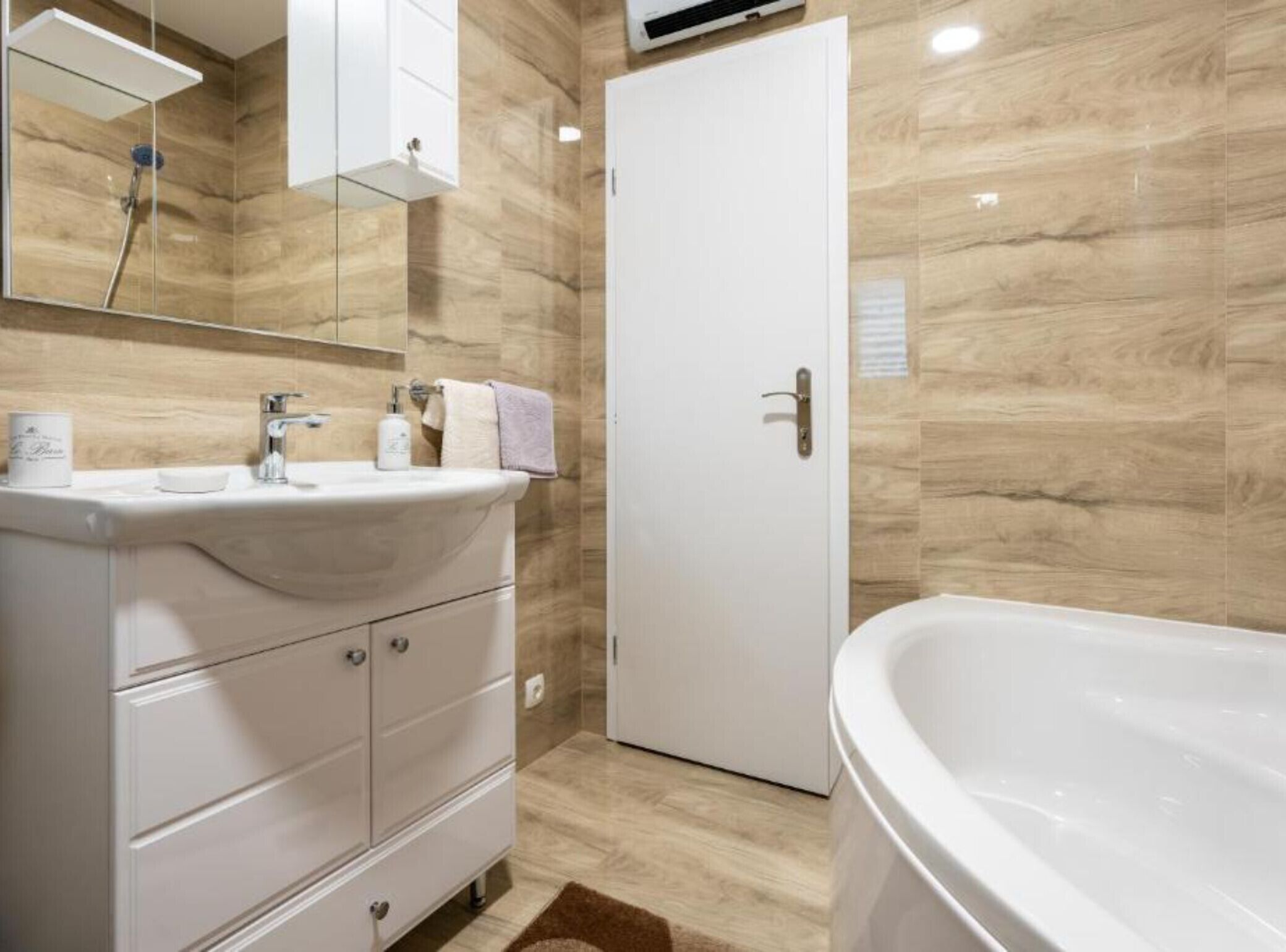 A modern bathroom with a freestanding bathtub, a vanity with a mirror, and a door.