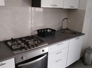 A kitchen with a gas stove, oven, sink, and white cabinets. - One Bedroom Apartment with Terrace (Povljana)