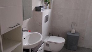 Ein Badezimmer mit weißem Waschbecken, WC und Mülleimer.