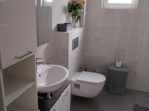 Ein Badezimmer mit weißem Waschbecken, WC und Mülleimer.