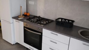 Eine Küche mit weißen Schränken, einem Gasherd, einem schwarzen Backofen und einer Arbeitsplatte mit einem Korb.