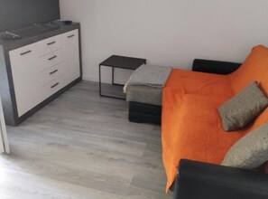 Ein modernes Zimmer mit einem grauen Sofa, einem kleinen schwarzen Tisch und einem grauen Schrank mit Schubladen.
