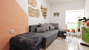 Una sala de estar con sofá, una mesita, un banco y una pared con textura similar a la piedra.