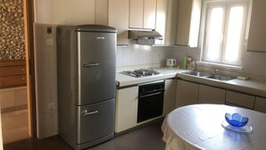 Une cuisine de taille réduite, équipée d’un réfrigérateur en acier inoxydable, d’un évier et d’une cuisinière.