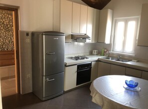 A compact kitchen with a stainless steel refrigerator, a sink, and a stove. - Two Bedroom Apartment with Terrace (Drasnice)