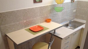 Een compacte keuken met een spoelbak, een kruk en een aanrecht.