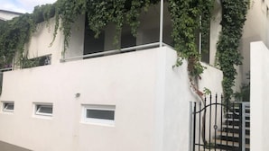 Un bâtiment à la façade blanche, doté d’une grille en métal et d’une petite fenêtre.