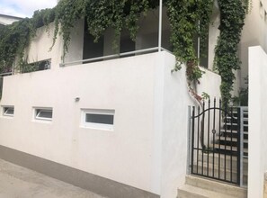 Ein Gebäude mit weißer Fassade, einem Metallgitter und einem kleinen Fenster.