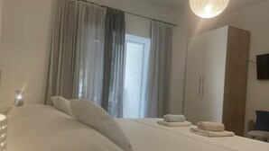 Une chambre d’hôtel avec un lit, une armoire, une télévision et une fenêtre avec des rideaux.