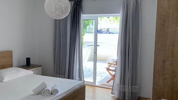 Une chambre avec un lit, une table de chevet, un luminaire suspendu et une vue sur un espace extérieur comprenant une chaise et un vélo.