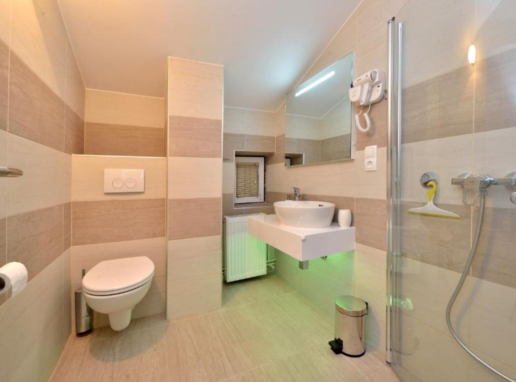 Une salle de bain moderne équipée de toilettes, d’un lavabo, d’une douche et d’un miroir.