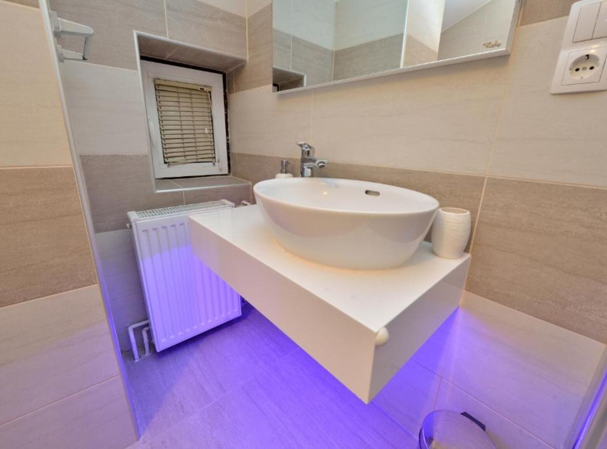Une salle de bain moderne avec un lavabo blanc, un miroir et un porte-rouleau de papier toilette.