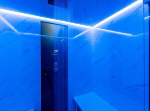 Een lift met een digitaal bedieningspaneel, een glazen deur en een blauw verlicht interieur.