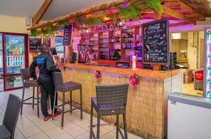 Un espace bar avec un comptoir, des tabourets de bar et un tableau affichant le menu.