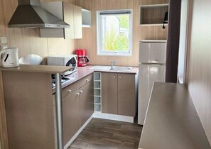 Une cuisine de taille réduite, équipée d’une cuisinière, d’un évier et d’une fenêtre.