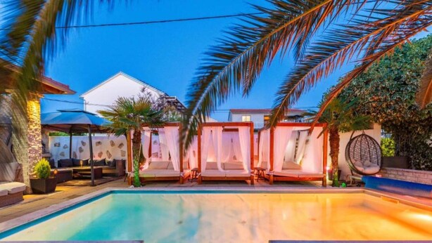 A swimming pool with lounge chairs and a covered seating area. - Obe Bedroom Apartment with Balcony (Sukosan)