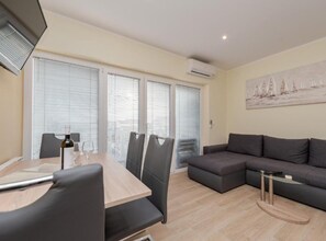 A modern living space with a dining area, a sofa, and a painting on the wall. - Superior Two Bedroom Apartment with Terrace (Sukosan)