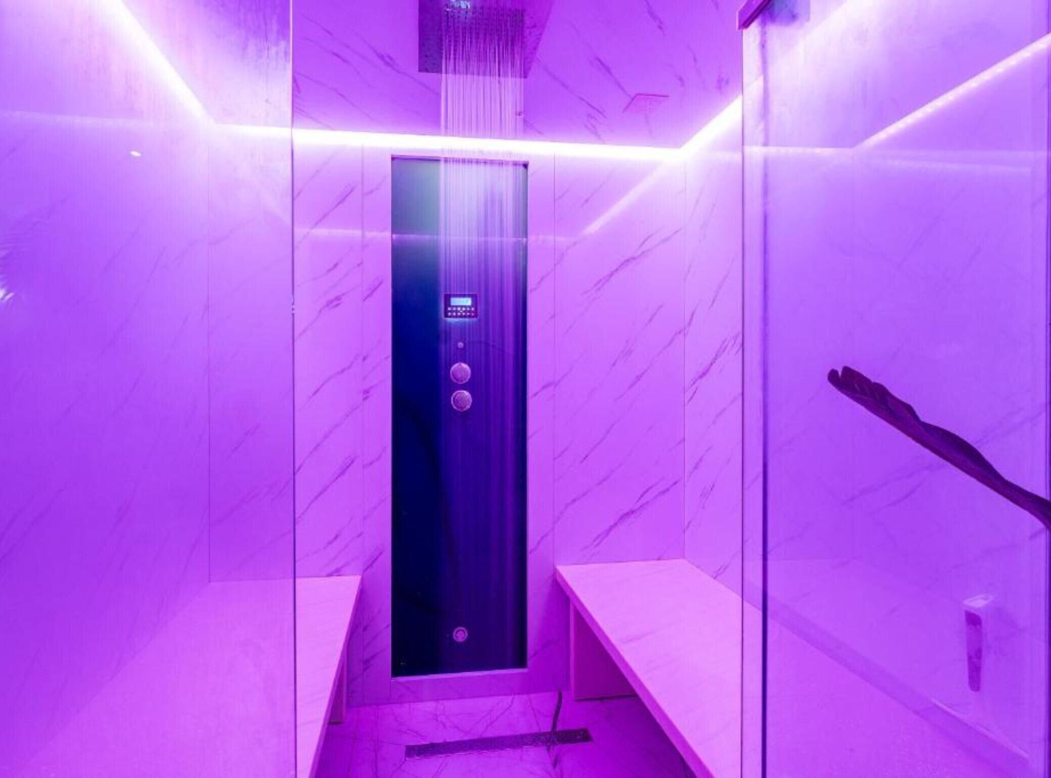 Un ascensor moderno con panel de control, paredes de mármol y un banco.