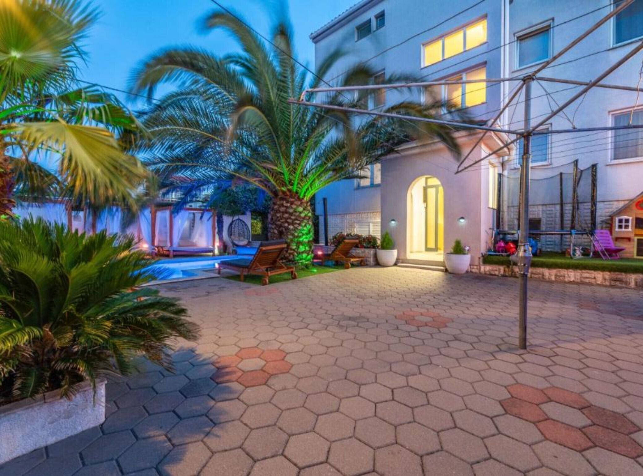 A hotel courtyard with a swimming pool, palm trees, and a covered seating area.