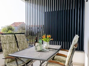 Ein Balkon mit Tisch, Stühlen und einem Blumentopf.