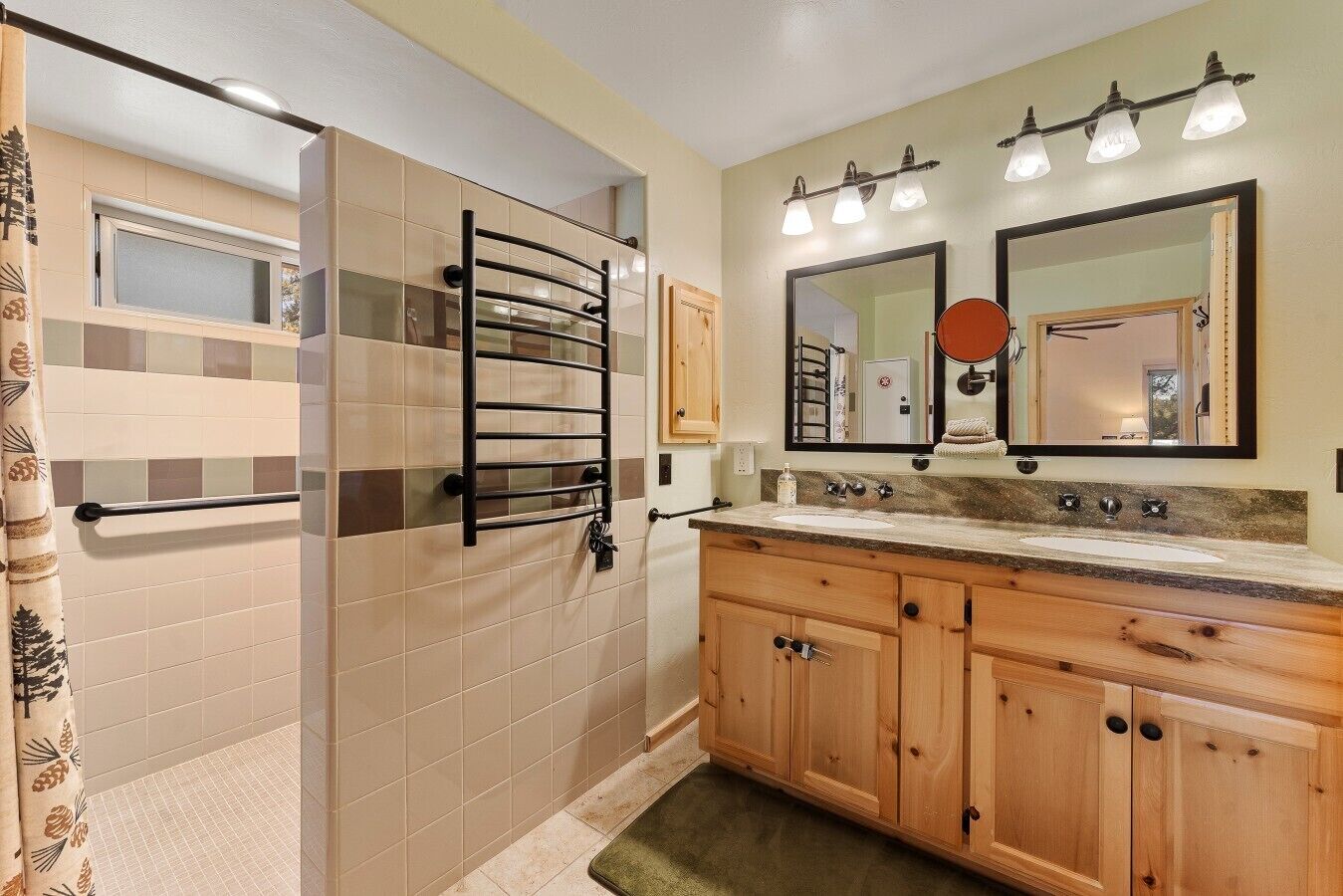 A bathroom with a shower, a vanity with a sink, and two mirrors.