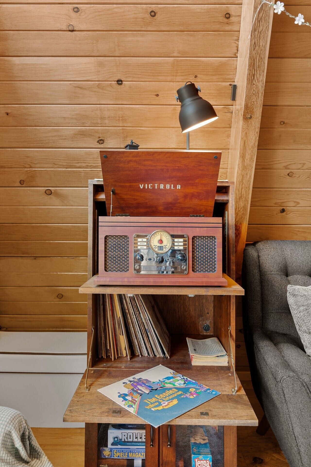 A wooden cabinet with a vintage radio, a lamp, and vinyl records.