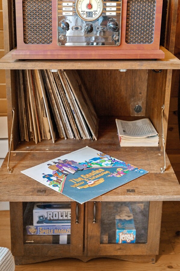 Un meuble en bois surmonté d’une radio ancienne, contenant des disques vinyle et un livre.