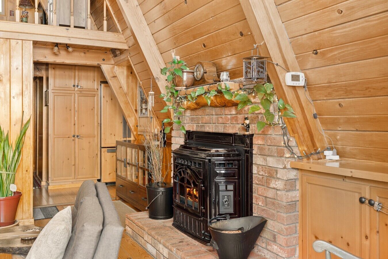 Une pièce chaleureuse avec une cheminée, des murs en bois et un escalier menant à un niveau supérieur.
