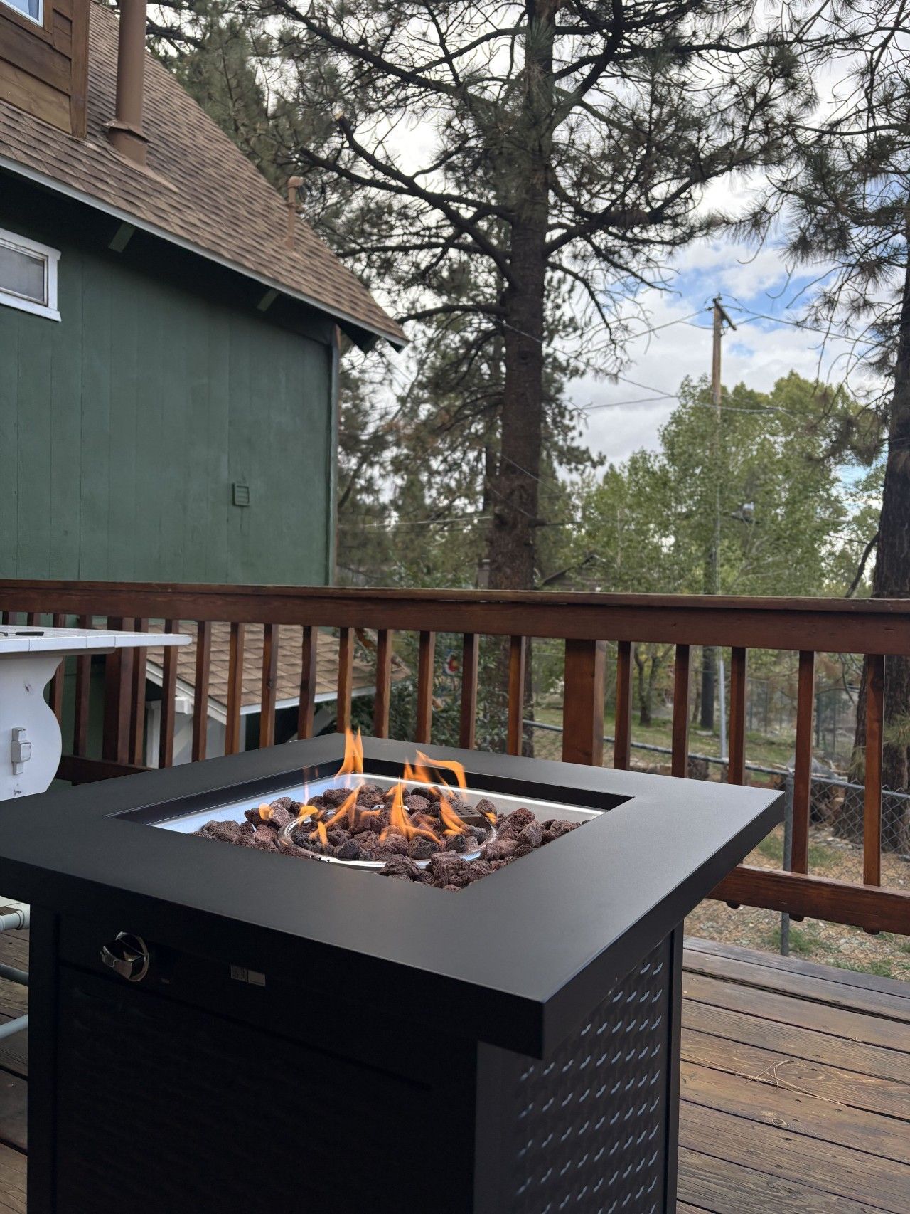 A deck with a metal fire feature and a wooden railing.