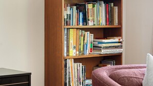 A bookshelf with a variety of books, a framed picture, and a sign indicating 'Ski Lodge'. - Pine & Peak | Cozy Cabin Getaway (Wrightwood)