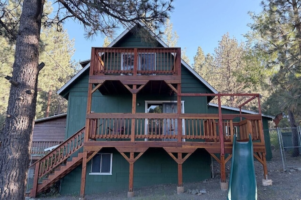 A cozy mountain retreat nestled among the pines! ✨ Wake up to pine trees, sip coffee on the deck, slide down the hill like you’re 10 again (yes, there’s a slide), and just exist in peace for a bit. 💚