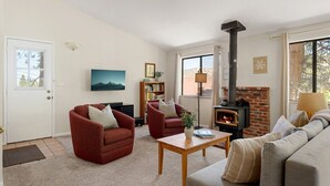 A living room with a fireplace, sofas, armchairs, a coffee table, and a bookshelf. - Pine & Peak | Cozy Cabin Getaway (Wrightwood)