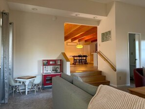 Una sala de estar con un sofá, una mesa de comedor y una escalera que lleva a otra habitación.