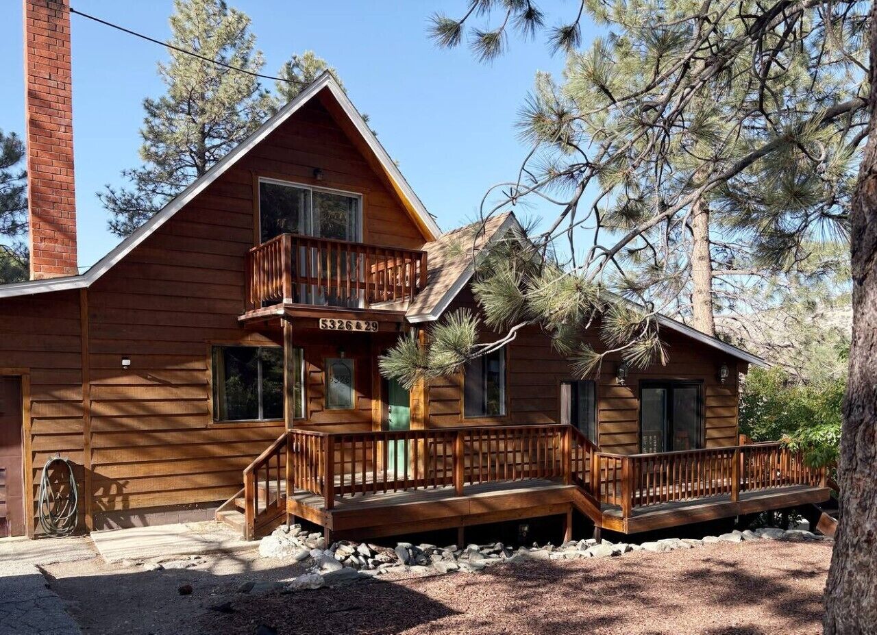 A wooden cabin with a balcony, a chimney, and a number '5326 29' on the front door.. Pine & Peak | Cozy Cabin Getaway