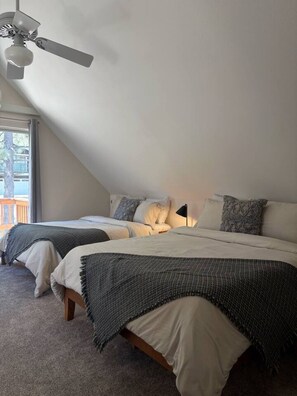 A bedroom with two beds, a ceiling fan, and a view of the outside. - Pine & Peak | Cozy Cabin Getaway (Wrightwood)