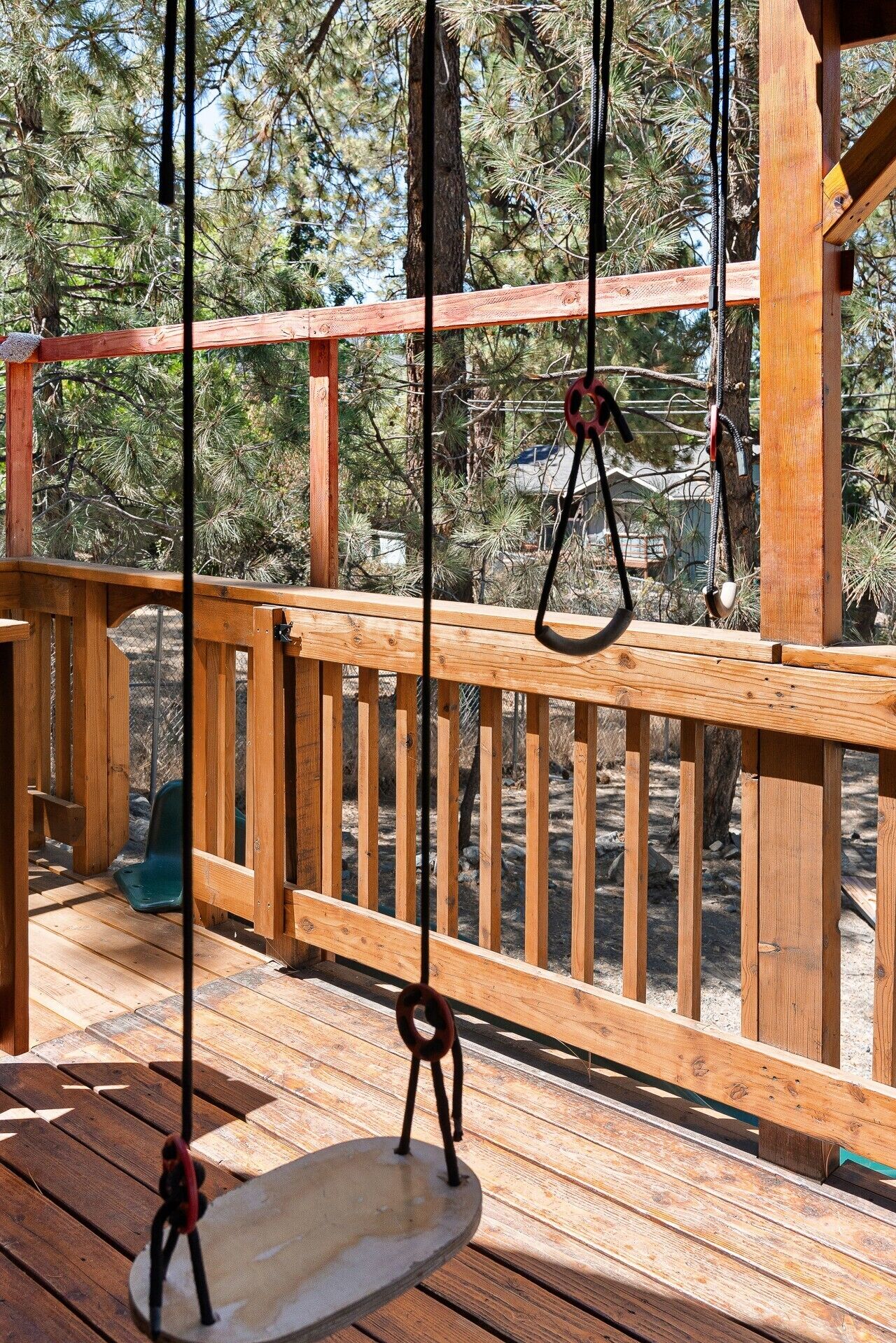 Una terraza de madera con un columpio y un tobogán.